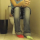 A hidden camera is set up on a bathroom floor to record a girl with unmatched socks taking a piss and a shit while sitting on a toilet. Plops are audible. About 7 minutes.